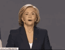 a woman stands at a podium in front of two flags with the words " de la candidate " on the bottom