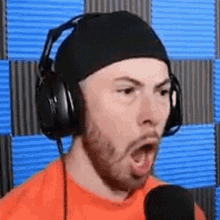 a man wearing headphones and a beanie is speaking into a microphone .