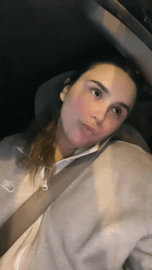 a woman wearing a grey nike sweatshirt is sitting in a car