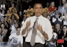 a man in a white shirt and tie stands in front of a crowd with a sign that says cnn