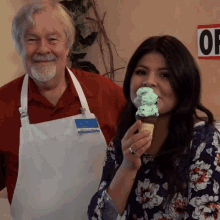 a man and a woman are standing next to each other and the woman is holding an ice cream cone with a mint flavor