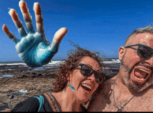 a man and woman are posing for a picture with a blue hand behind them