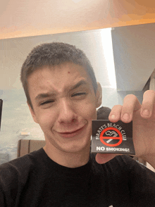 a young man holds up a sticker that says pirates beach club no smoking