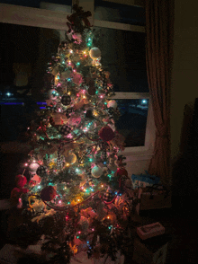 a christmas tree in a dark room with gifts underneath it