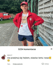 a man in a red jacket and shorts is standing in front of a wooden wall