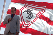 a man in a suit stands in front of a flag that says samsunspor