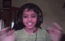 a young boy wearing headphones and a microphone is smiling and making a funny face .