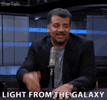 a man sitting in front of a microphone with the words light from the galaxy written below him