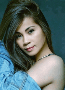 a close up of a woman 's face with a denim jacket over her shoulder