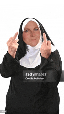 a woman dressed as a nun is giving the middle finger .