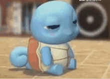 squirtle is sitting on the floor with his eyes closed and looking at the camera .