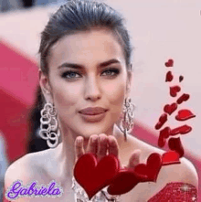 a woman in a red dress is blowing a kiss while holding a heart in her hand .