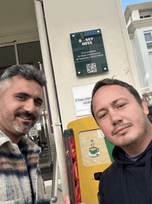 two men standing in front of a sign that says bossy nuits