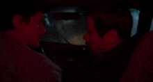 two men are sitting in a car and talking to each other .