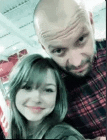 a man and a woman are posing for a picture together . the woman is smiling and the man is looking at the camera .