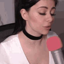 a woman wearing a choker is talking into a microphone .