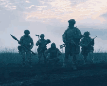 a group of soldiers standing next to each other in a field holding guns .