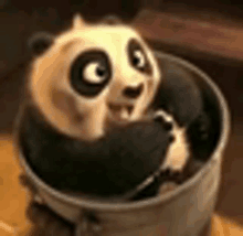 a panda bear is sitting in a bucket on a table .