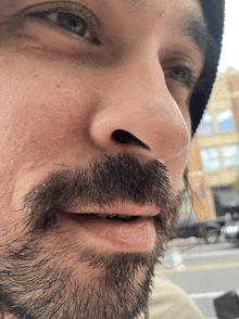 a close up of a man 's face with a beard and a beanie