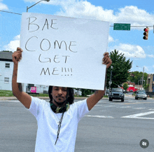 a man holds a sign that says bae come get me