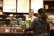 a woman at a starbucks counter with a sign that says starbucks gold on it