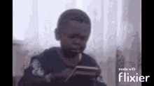 a young boy is sitting in front of a window playing a game on a tablet .