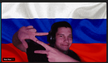 a man in front of a russian flag making a peace sign with his fingers