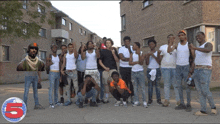 a group of young men are posing for a picture in front of a building with the number 5 in the corner