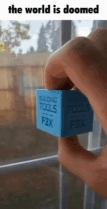 a person is holding a blue cube with the words building tools on it .