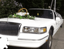 a white lincoln limousine with flowers and wedding rings on the hood