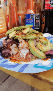 a blue bottle of mexico lindo sits on a table next to a plate of food