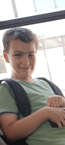 a young boy with a backpack is sitting in a bus and smiling .