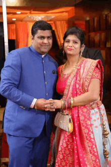 a man in a blue suit and a woman in a red dress pose for a photo