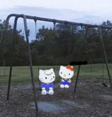 two hello kitty dolls sitting on a swing set in a park