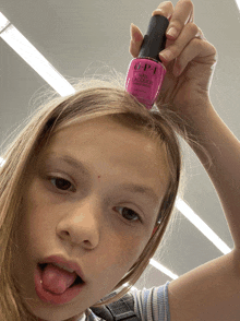 a young girl holds a bottle of opi nail polish in her hair