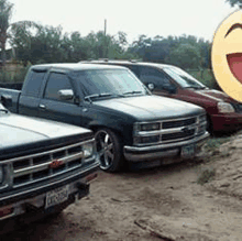 a row of cars are parked in a dirt lot next to a smiley face statue .