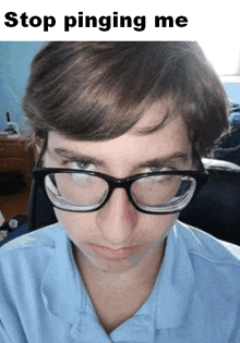 a young man wearing glasses and a blue shirt is looking at the camera .