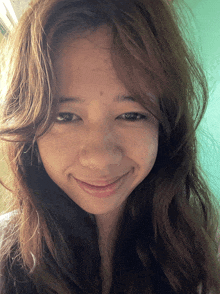 a girl with long brown hair looks at the camera with a smile on her face