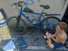 a boy sits on the sidewalk next to a bicycle and a toolbox that says ' bosch ' on it