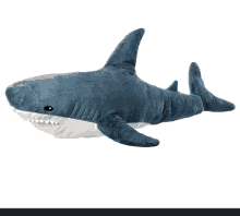 a stuffed shark with sharp teeth is laying on a white background