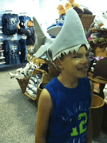 a young boy wearing a shark hat and a blue shirt with the number 12