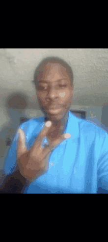 a man wearing a blue shirt is giving the peace sign