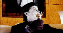 a man in a joker costume is drinking a glass of wine