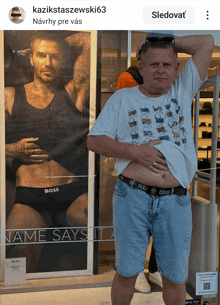 a man stands in front of a poster of a man wearing underwear that says boss on it