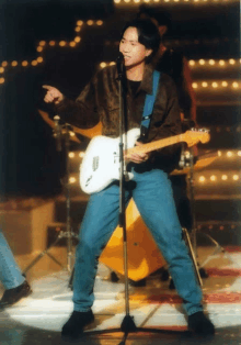 a man is singing into a microphone while holding a white guitar