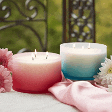 two candles are sitting on a table with pink flowers