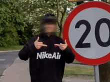 a person wearing a black nike air sweatshirt stands in front of a sign that says 20