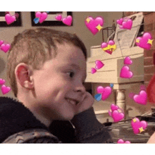 a young boy is sitting in front of a piano with pink hearts floating around him .