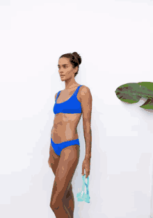 a woman in a blue bikini holds a pair of goggles