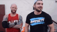 two men are standing next to each other and one of them is wearing a shirt that says impact wrestling